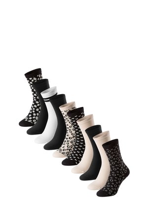 Neuf paires de chaussettes mi-mollet en noir, blanc, beige et à motifs animaliers ou géométriques disposées en ligne diagonale sur un fond blanc.