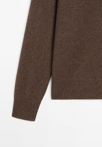 Pull en maille marron avec une texture douce. Il présente un ourlet et des poignets côtelés. Le tissu semble chaud et convient pour le superposition.
