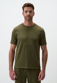 T-shirt a maniche corte di colore verde oliva con scollo rotondo, realizzato in un tessuto morbido, presenta un design aderente con cuciture lisce e orlo dritto.