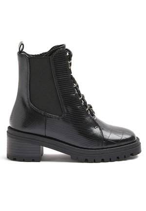 Bottine noire en cuir texturé avec talon épais, lacets sur le devant et panneau latéral élastique pour un enfilage facile.