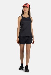 Czarny sportowy top na ramiączkach i szorty o gładkiej fakturze. Zawiera dwukolorową czapkę z czerwoną przednią łatą i siateczkowym tyłem. Czarne buty do biegania.