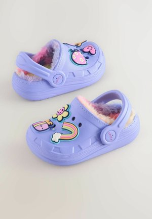 Lila Clogs mit einem flauschigen Innenfutter, verziert mit bunten Kunststoffapplikationen wie Blumen, Herzen und einem Regenbogen, mit einem Hinterriemen.