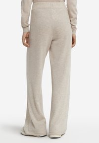 Ljust beige loungebyxor i mjukt material, med lös passform, elastisk midja och diskret textur för komfort.