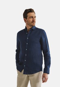 Navyblauw linnen shirt met een button-down kraag en lange mouwen. Bevat lichtblauwe knopen en heeft een relaxte pasvorm met een gestructureerde afwerking.