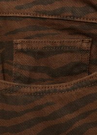 Brun denimtyg med ett subtilt tigerstripe-mönster. Har en ficka med synlig sömnad och en mjuk textur.