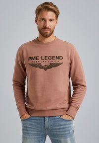 Bruine sweatshirt met ronde hals, voorzien van een opdruk met "PME LEGEND AMERICAN CLASSIC" en vleugelgraphics.