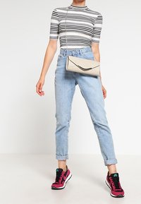 Harmaa ja musta raidallinen lyhythihainen paita, vaaleansiniset korkeavyötäröiset farkut ja vaaleanpunaiset lenkkitossut. Pieni béžin värinen olkalaukku on käytössä.