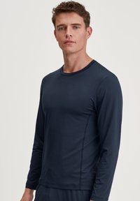 Marineblauwe lange mouwen shirt van zachte stof, met een ronde hals en subtiele zijkanten, ontworpen voor een aansluitende pasvorm.