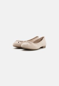 Ballerines beiges en daim doux avec un bout rond, un accent en nœud et un petit matériel décoratif. Semelle plate pour le confort.