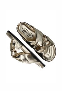 Metalen gouden slip-on sandalen met een geknoopte voorkant, zwarte zool en een gladde textuur. Gedrukt logo zichtbaar op de binnenzool.