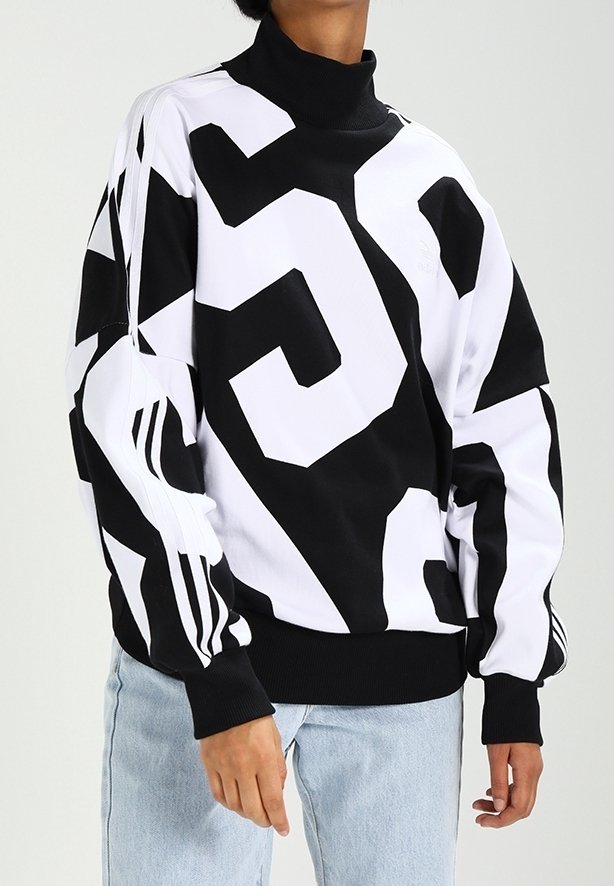 Schwarz-weißer Pullover mit hohem Kragen, kräftigen geometrischen Mustern und drei Streifen an den Ärmeln. Weicher Stoff mit lockerem Schnitt.