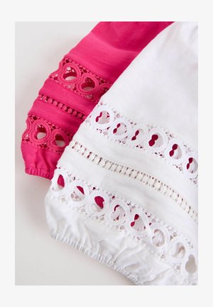 Biele a ružové látkové rukávy s čipkovanými vzormi v tvare srdca a nariasenými elastickými manžetami.