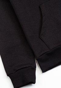 Manches de sweat-shirt noir avec poignets côtelés à côté d'une poche kangourou avant sur fond blanc.
