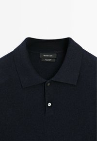 Navyblaue Kaschmir-Polo-Shirt mit klassischem Kragen, zwei Knöpfen und einer weichen, strukturierten Oberfläche. Markenlabel am Hals sichtbar.