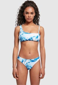 Bikini set u plavom mramornom uzorku, s topom na jedno rame i donjim dijelovima s niskim strukom. Glatka tkanina s mekim osjećajem.
