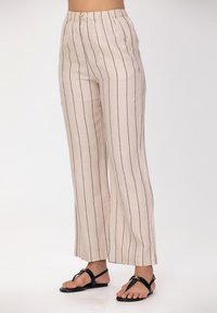 Pantalon large en mélange de lin de couleur beige clair avec des rayures verticales bleu marine, doté d'une ceinture élastique et d'une coupe décontractée.