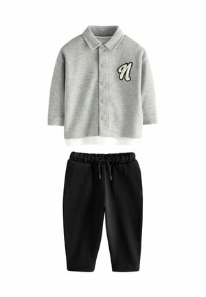 Grijs collared top met knoopsluiting en geborduurd "N," gecombineerd met zwarte jogger-stijl broek met elastische tailleband.