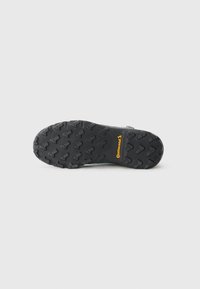 Semelle en caoutchouc noire avec un motif de crampons robuste pour une meilleure traction. Logo "Continental" en jaune bien visible sur le côté.