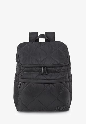 Mochila negra acolchada con forma cuadrada, que cuenta con una solapa superior, dos compartimentos con cremallera y un logo en la esquina inferior derecha.