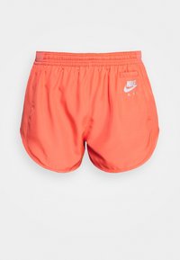 Bermudas Nike de color coral brillante con cinturilla elástica, aberturas laterales y un pequeño logo blanco. Presentan una tela suave y ligera.