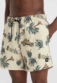 Beige uima-shortsit, joissa on trooppinen kuvio, jossa on kirahveja, palmupuuta ja vintage-rekkoja. Musta naru ja sivutaskut mukana.