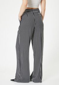 Zwart-witte gestreepte wijde broek met voorzakken en een hoge tailleband, met een gladde stoftextuur en een losse pasvorm.