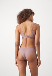 Ensemble de sous-vêtements mauve comprenant un bikini sans couture et un soutien-gorge ajustable avec des bretelles larges, un tissu lisse et une fermeture à crochets.