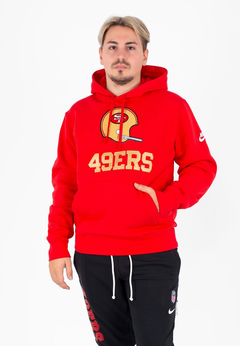 Czerwony hoodie wykonany z mieszanki bawełny z kieszenią z przodu, z złotym logo "49ERS" i grafiką hełmu futbolowego. Czarne dresy z białym sznurkiem.