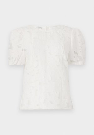 Hvid bluse med tekstureret stof, korte puffærmer, rund halsudskæring og et diskret blomstermønster. Bagtil med lynlåslukning.