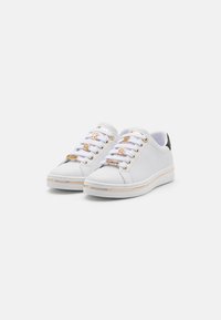 White sneakers with a smooth leather exterior, gold-tone hardware on laces, minimalistic design, and a slim white rubber sole with a gold accent.