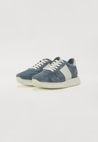 Baskets en daim bleu foncé avec des accents crème, présentant un bout arrondi, un design à lacets et une semelle texturée. Style athlétique classique.