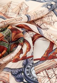 Bufanda de seda multicolor con un diseño detallado de carrusel, con caballos vibrantes y patrones intrincados sobre un fondo beige.