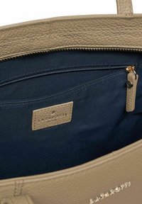 Interno di una borsa in pelle beige con texture, foderato in tessuto blu navy, dotato di una tasca con zip e di un'etichetta del brand cucita con la scritta "Lazarotti."