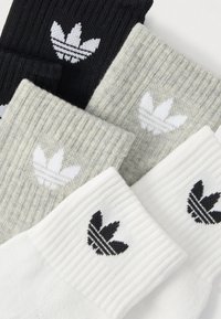 Cinco pares de meias em preto, cinza e branco com textura canelada. Cada uma apresenta o logótipo trevo da Adidas em preto ou branco na aba.