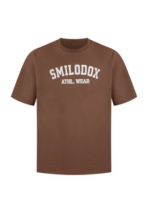 T-shirt en coton marron avec le texte blanc "SMILODOX ATHL. WEAR" dans un design en arc. Col rond et manches courtes. Texture lisse.