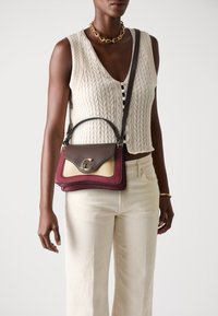 Sac à main en cuir brun et bordeaux avec un logo doré, présentant une surface texturée et un design superposé. Accompagné d'une bandoulière.