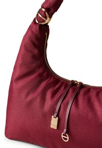 Burgundy leather shoulder bag with a textured finish, gold hardware accents, and a zipper closure; features knotted strap for carrying.