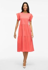 Robe midi en coton corail avec des manches courtes et évasées, taille froncée et jupe à volants. Texture lisse et coupe décontractée.