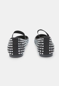 Mustat samettikenkä, joissa on kirkkaat rhinestone-koristeet takana ja sivuilla. Sisältää takaremmin varman istuvuuden vuoksi.