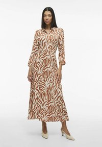 Robe à motif marron et crème avec des manches longues et une fermeture à boutons, fabriquée en tissu léger, présentant une longueur maxi fluide.