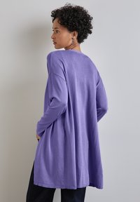 Lavendelfärgad långärmad topp med en avslappnad passform, rundad halsringning och en flödande design. Mjuk tyg med ribbade fållen.