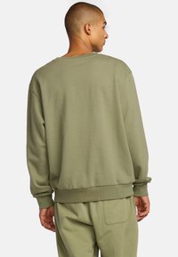 Olivgrüner Pullover aus weichem Stoff, mit lockerer Passform, gerippten Bündchen und Saum sowie einem Rundhalsausschnitt. Keine sichtbaren Logos oder Muster.