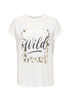 Joven con el pelo largo que lleva una camiseta blanca con estampado "wild", pantalones cortos negros con dobladillo festoneado, sandalias negras y pulseras en la muñeca.