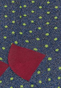 Calzini lavorati a maglia in blu con pois verdi, con rinforzo al tallone color marrone scuro. Morbida texture, con finitura liscia e cuciture precise.