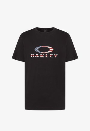 Maglietta nera in cotone con un grande logo a forma ovale in rosso, bianco e blu, e la parola "OAKLEY" in lettere grassetto sotto.
