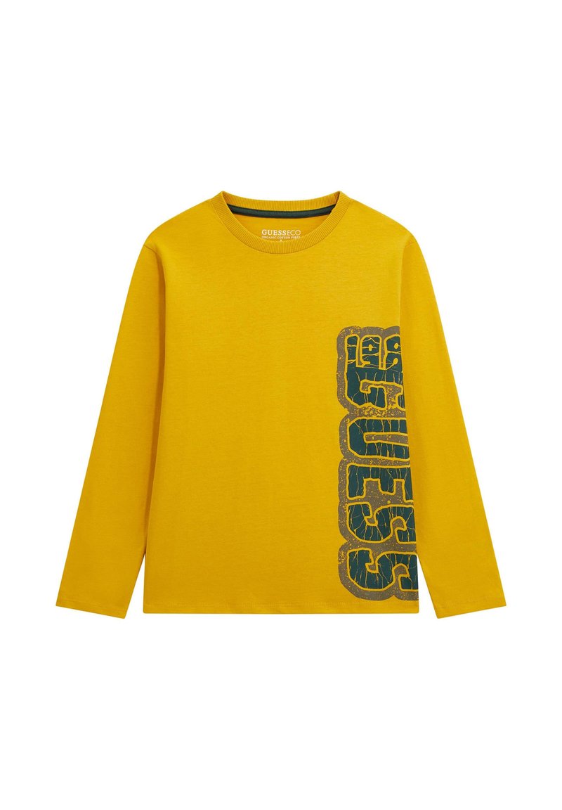 Żółta longsleeve z nadrukiem "GUESS" w pionie w przetartych czarnych literach po prawej stronie.