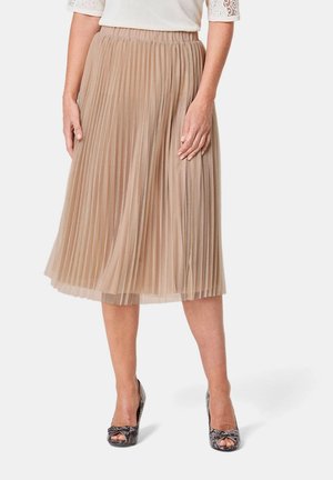 Jupe midi plissée en beige clair, fabriquée à partir d'un tissu fluide, dotée d'une taille élastique. Portée avec des talons ouverts à motifs.