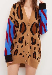 Brun cardigan med leopardtryck, med blå och röda randiga ärmar, en djup V-hals och träknappar. Tillverkad av mjukt stickat material.