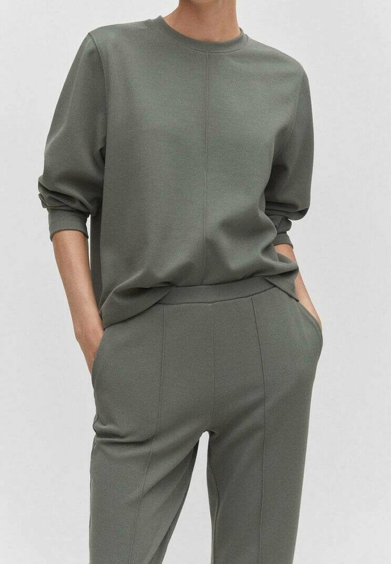 Felpa verde oliva e pantaloni abbinati, caratterizzati da una vestibilità rilassata, spalle cadenti e un tessuto testurizzato con una finitura liscia.