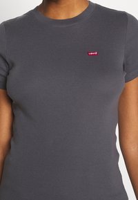 Grå kortærmet t-shirt lavet af blødt bomuldsstof, med et lille rødt Levi's-logo på brystet. Enkel, tætsiddende design med rund halsudskæring.